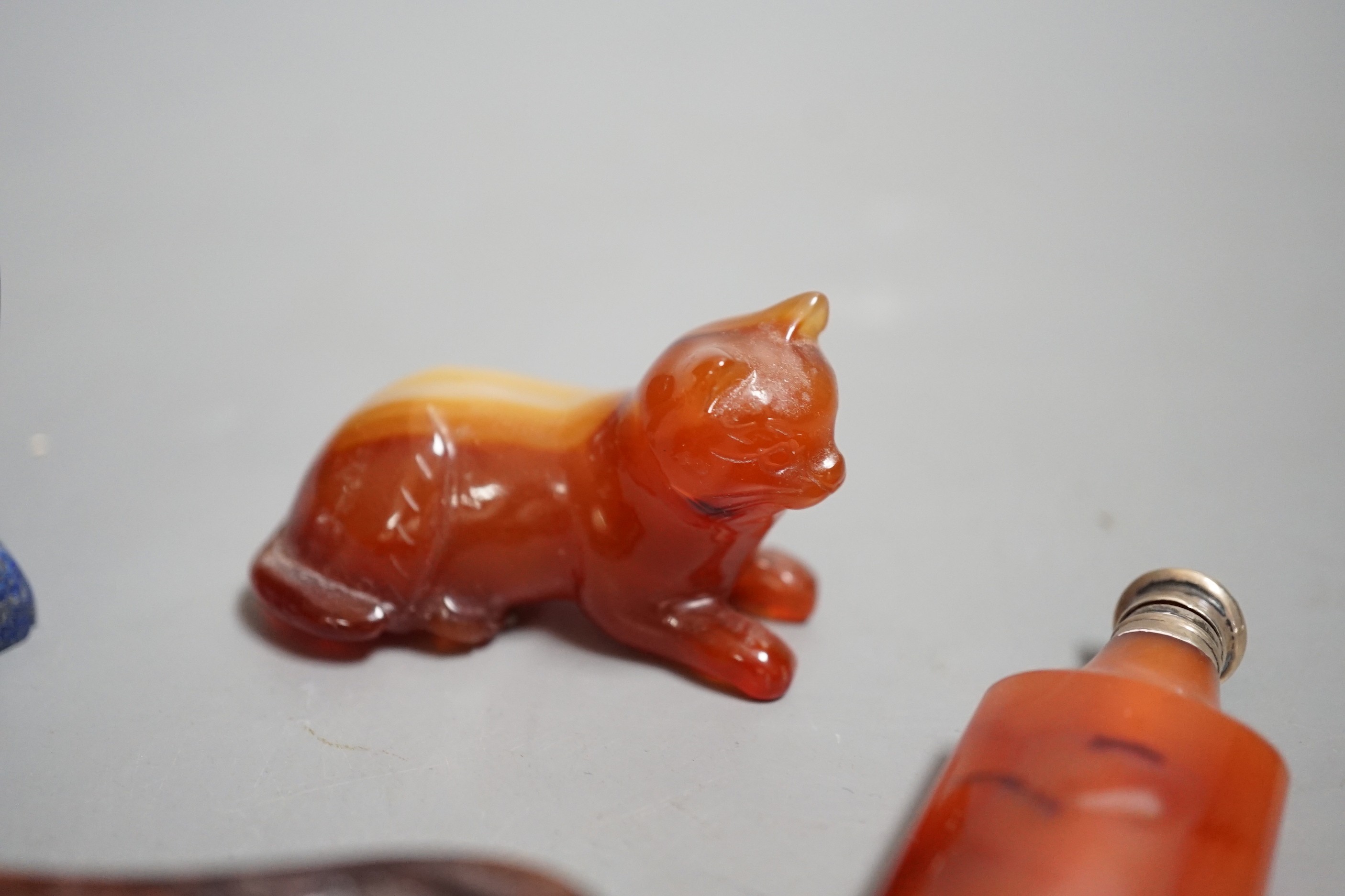 A Chinese carved lapis lazuli seated cat, a banded agate recumbent cat on hardwood stand and a white metal mounted agate scent bottle